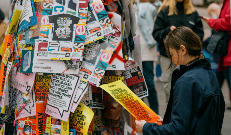 Girl Looking At Wall Of Poster Flyers